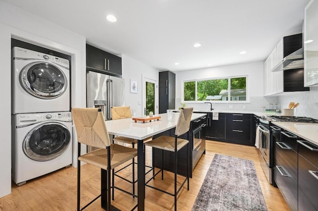 1010 Karen Ave, Austin, TX 78757 - kitchen with appliances with stainless steel finishes, stacked washer / dryer, dark cabinets, a center island, and recessed lighting