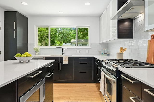 1010 Karen Ave, Austin, TX 78757 - kitchen with stainless steel appliances, light countertops, dark cabinetry, under cabinet range hood, and recessed lighting