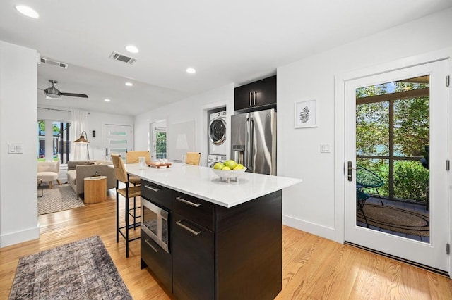 1010 Karen Ave, Austin, TX 78757 - kitchen featuring stacked washer / dryer, stainless steel appliances, dark cabinets, a breakfast bar area, and healthy amount of natural light