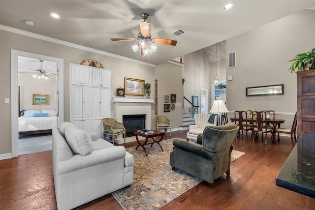 7815 Moritz Ln, Austin, TX 78731 - living room featuring ceiling fan, a glass covered fireplace, dark wood-type flooring, ornamental molding, and stairs