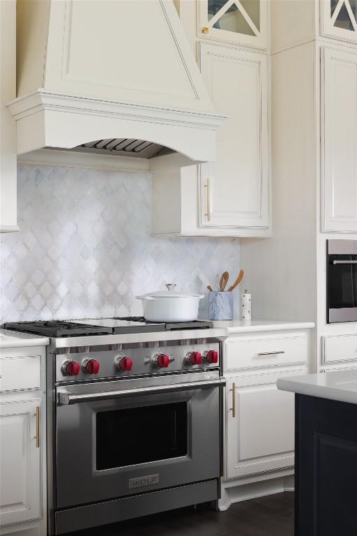 303 Marina View Ct Unit 23A, Austin, TX 78734 - kitchen with premium range, premium range hood, light countertops, white cabinetry, and decorative backsplash