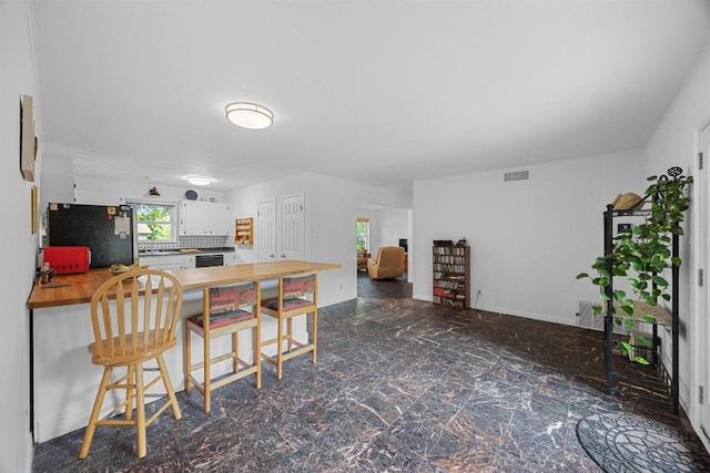 1209 Clearfield Dr, Austin, TX 78758 - kitchen featuring freestanding refrigerator, wooden counters, white cabinets, a peninsula, and a kitchen breakfast bar