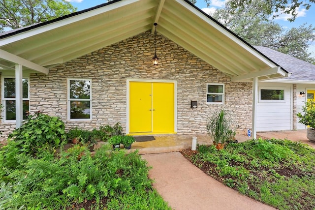 1209 Clearfield Dr, Austin, TX 78758 - view of exterior entry with stone siding, an attached garage, and a shingled roof