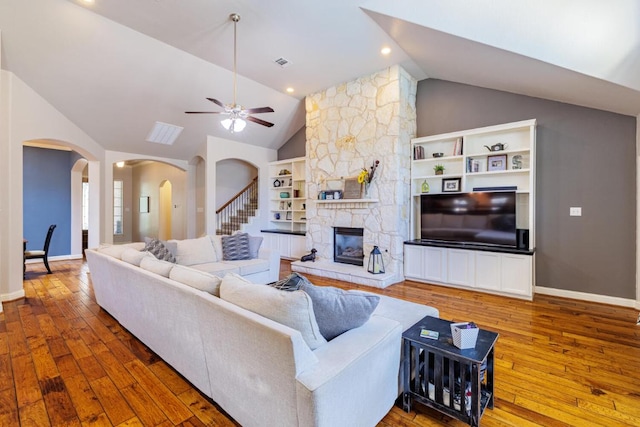 2843 Nolina Ln, Round Rock, TX 78681 - living room featuring vaulted ceiling, arched walkways, hardwood / wood-style floors, a ceiling fan, and a stone fireplace