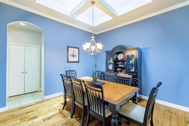 2843 Nolina Ln, Round Rock, TX 78681 - dining room with arched walkways, a skylight, crown molding, light wood-style flooring, and a chandelier