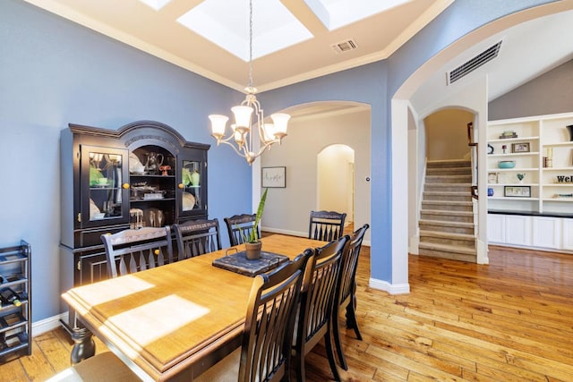 2843 Nolina Ln, Round Rock, TX 78681 - dining space featuring arched walkways, crown molding, light wood finished floors, a chandelier, and stairway