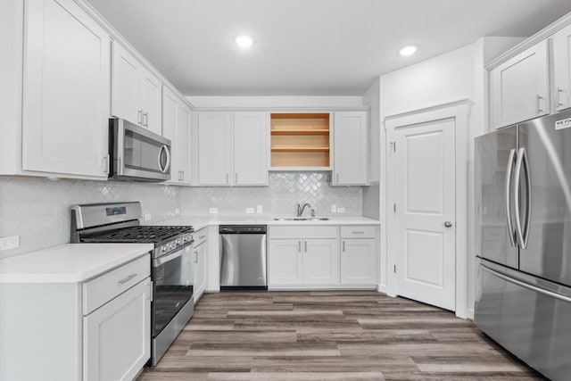225 Lambert St, Leander, TX 78641 - kitchen featuring appliances with stainless steel finishes, open shelves, light countertops, tasteful backsplash, and wood finished floors