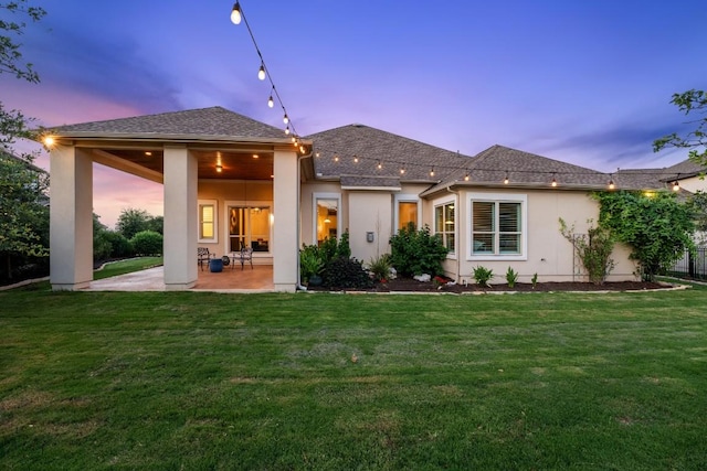 1821 Gilded Crest Dr, Leander, TX 78641 - back of house at dusk with a patio, stucco siding, and a yard