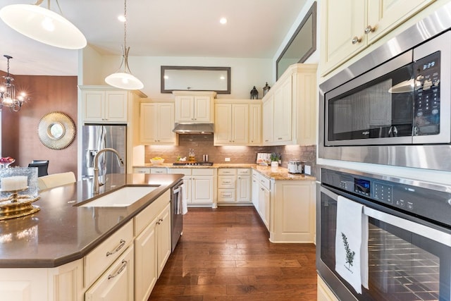 1821 Gilded Crest Dr, Leander, TX 78641 - kitchen with stainless steel appliances, cream cabinets, decorative backsplash, dark wood-style flooring, and recessed lighting