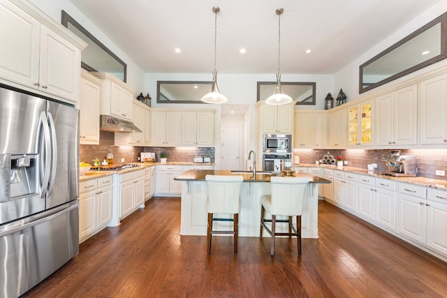 1821 Gilded Crest Dr, Leander, TX 78641 - kitchen with appliances with stainless steel finishes, backsplash, under cabinet range hood, a center island with sink, and recessed lighting