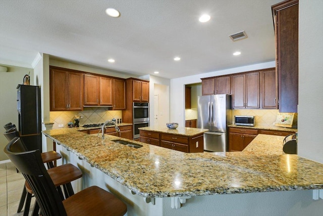 203 Mustang Island Trl, Georgetown, TX 78633 - kitchen with stainless steel appliances, light stone countertops, a peninsula, tasteful backsplash, and recessed lighting
