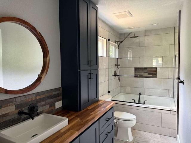 6609 Capriola Dr, Austin, TX 78745 - full bathroom with tiled shower / bath, double vanity, and a textured ceiling