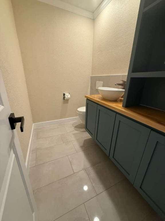 6609 Capriola Dr, Austin, TX 78745 - bathroom with a textured wall, ornamental molding, vanity, and tile patterned flooring