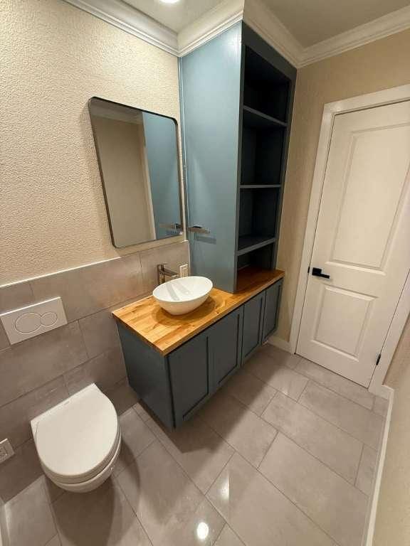 6609 Capriola Dr, Austin, TX 78745 - bathroom featuring crown molding, vanity, and tile walls