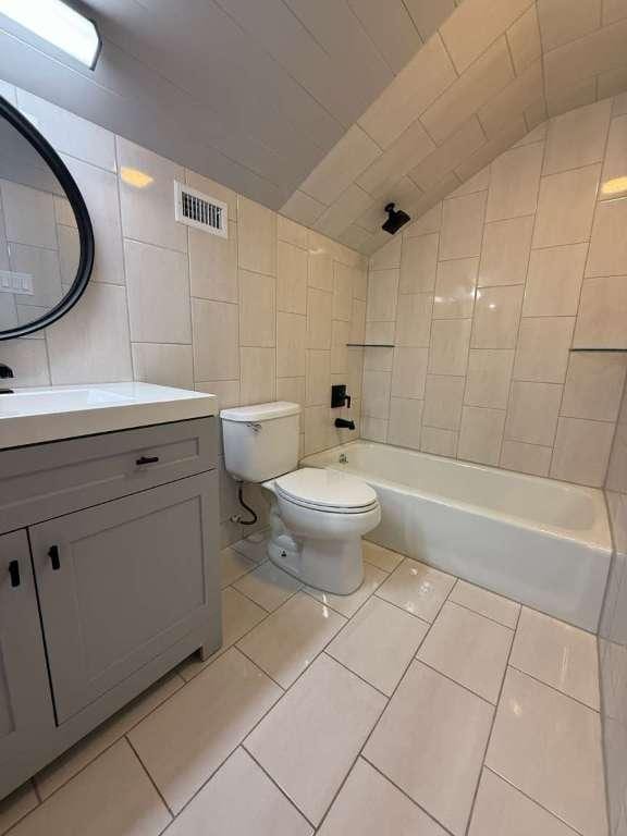 6609 Capriola Dr, Austin, TX 78745 - full bathroom with vanity, tile walls, lofted ceiling, shower / tub combination, and tile patterned floors