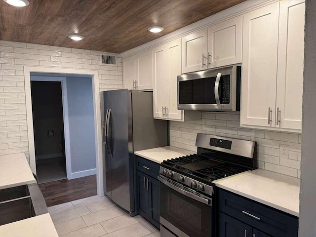 6609 Capriola Dr, Austin, TX 78745 - kitchen featuring appliances with stainless steel finishes, wood ceiling, white cabinetry, backsplash, and light tile patterned flooring
