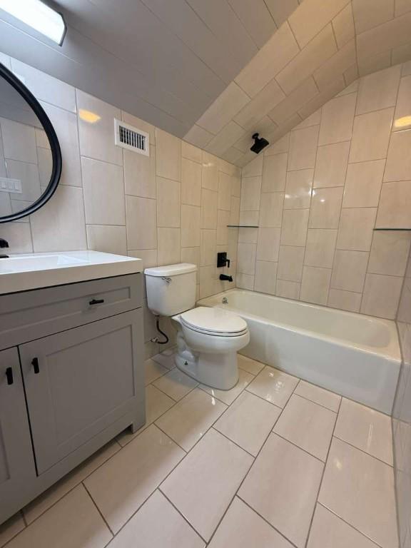 6609 Capriola Dr, Austin, TX 78745 - full bathroom with vanity, lofted ceiling, tile walls, bathing tub / shower combination, and tile patterned flooring