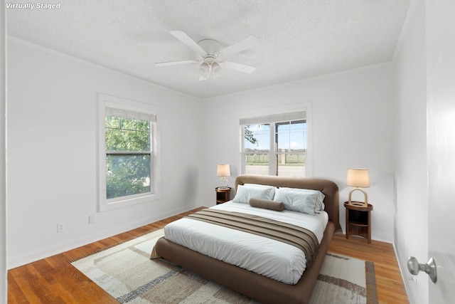 506 W 51st St Unit A, Austin, TX 78751 - bedroom with multiple windows, ornamental molding, wood finished floors, a textured ceiling, and ceiling fan