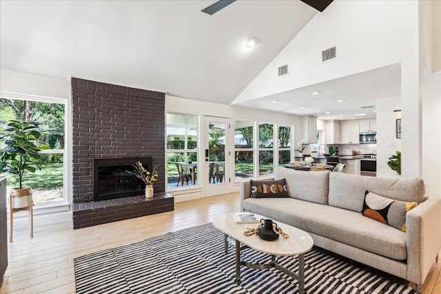 11308 Toledo Dr, Austin, TX 78759 - living room with healthy amount of natural light, a fireplace, high vaulted ceiling, and light wood-style flooring