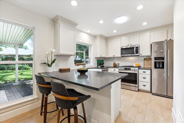 11308 Toledo Dr, Austin, TX 78759 - kitchen featuring appliances with stainless steel finishes, dark countertops, a peninsula, decorative backsplash, and white cabinets