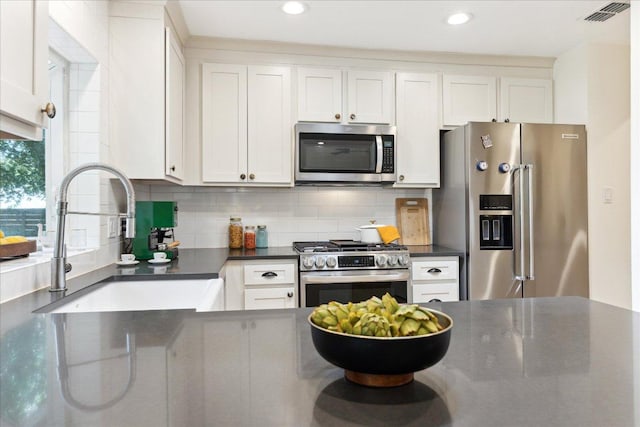 11308 Toledo Dr, Austin, TX 78759 - kitchen featuring appliances with stainless steel finishes, dark countertops, white cabinetry, tasteful backsplash, and recessed lighting