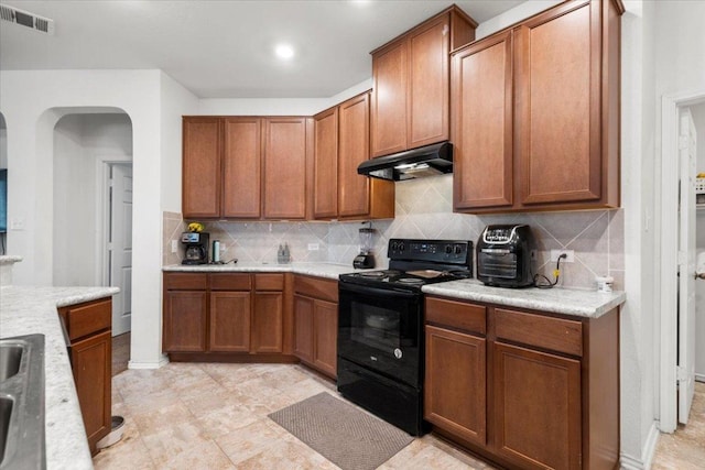 239 Crimson Ln, Kyle, TX 78640 - kitchen with electric range, under cabinet range hood, arched walkways, and light countertops