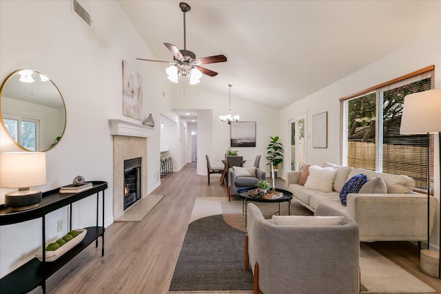 12806 Heinemann Dr, Austin, TX 78727 - living area featuring ceiling fan, light wood-style floors, a tiled fireplace, a chandelier, and high vaulted ceiling