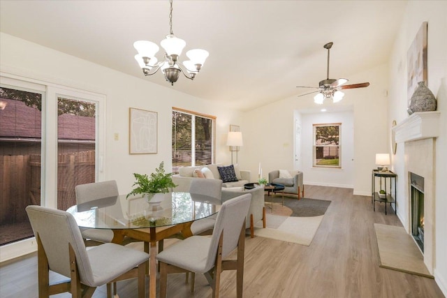 12806 Heinemann Dr, Austin, TX 78727 - dining space featuring a chandelier, light wood-type flooring, a warm lit fireplace, ceiling fan, and lofted ceiling