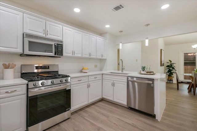 12806 Heinemann Dr, Austin, TX 78727 - kitchen featuring appliances with stainless steel finishes, light countertops, light wood-style flooring, a peninsula, and recessed lighting