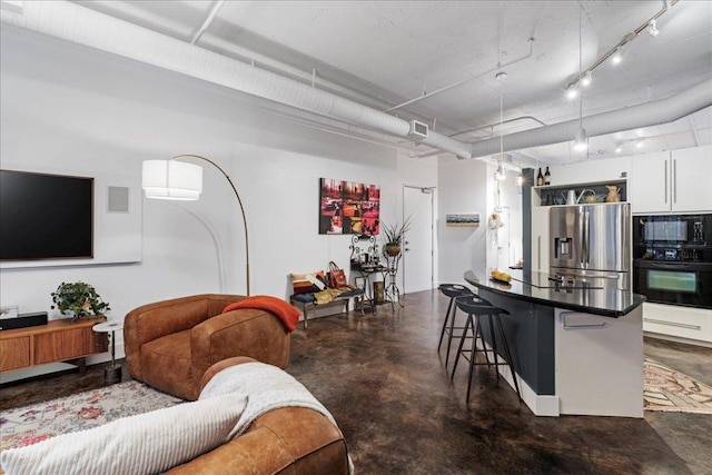 311 W 5th St Unit 1008, Austin, TX 78701 - kitchen featuring black appliances, finished concrete flooring, a kitchen bar, white cabinets, and dark countertops