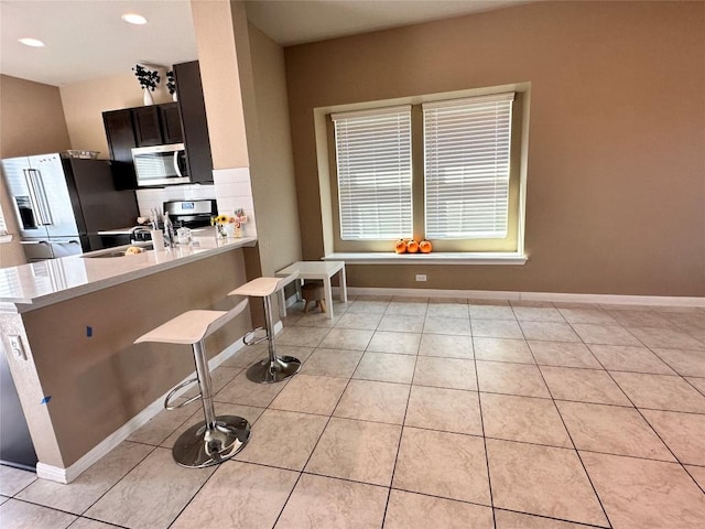 125 Duck Creek Trl, San Marcos, TX 78666 - kitchen with stainless steel appliances, light countertops, a kitchen breakfast bar, light tile patterned floors, and recessed lighting
