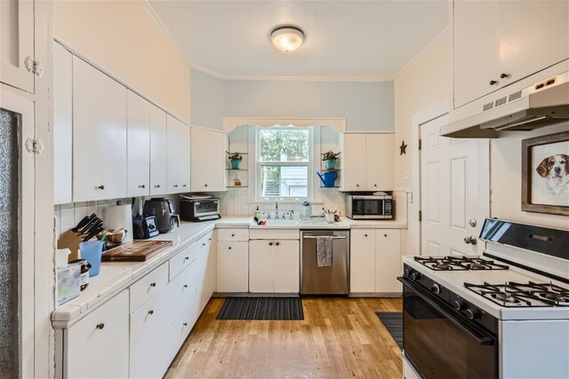 1508 Pease Rd, Austin, TX 78703 - kitchen with appliances with stainless steel finishes, under cabinet range hood, light countertops, ornamental molding, and backsplash