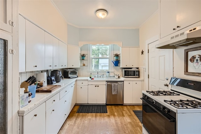 1508 Pease Rd, Austin, TX 78703 - kitchen with appliances with stainless steel finishes, under cabinet range hood, light countertops, ornamental molding, and decorative backsplash