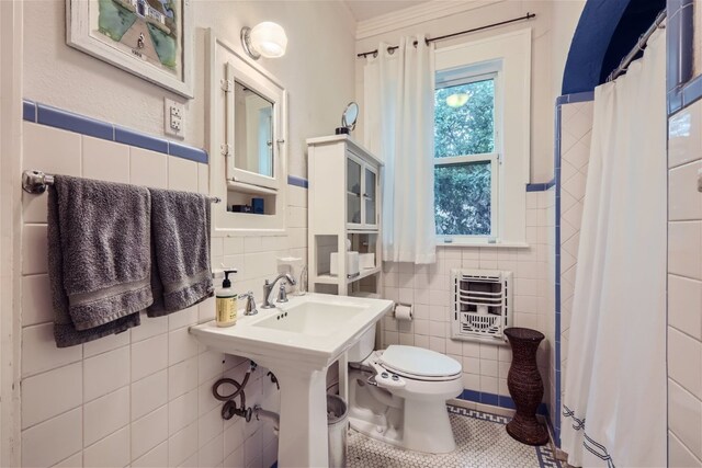1508 Pease Rd, Austin, TX 78703 - full bath featuring tile walls, heating unit, a shower with curtain, tile patterned flooring, and wainscoting