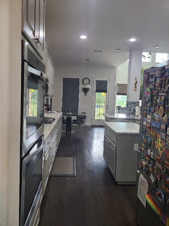 608 Cascada Ln, Round Rock, TX 78681 - kitchen with dark wood finished floors, stainless steel double oven, tasteful backsplash, recessed lighting, and light stone counters