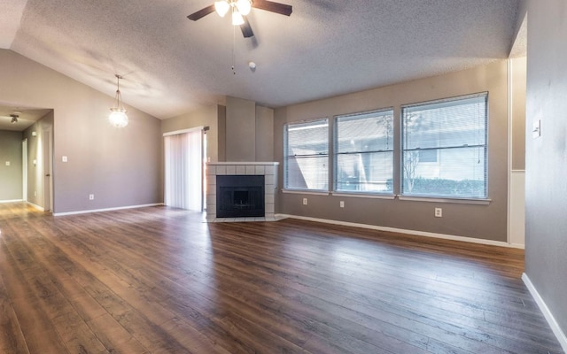 1007 Markham Ln Unit A, Austin, TX 78753 - unfurnished living room with a textured ceiling, a ceiling fan, dark wood finished floors, lofted ceiling, and a tile fireplace
