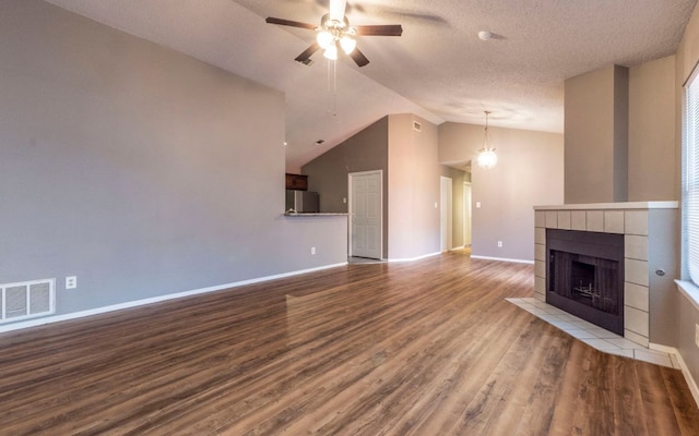 1007 Markham Ln Unit A, Austin, TX 78753 - unfurnished living room with ceiling fan, wood finished floors, vaulted ceiling, a tile fireplace, and a textured ceiling