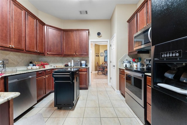 3516 Valley Mist Ct, Temple, TX 76502 - kitchen with stainless steel appliances, light tile patterned floors, decorative backsplash, and light stone counters