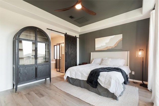 2624 San Bautista Way Unit 44, Leander, TX 78641 - bedroom featuring a barn door, wood finished floors, ceiling fan, and a tray ceiling