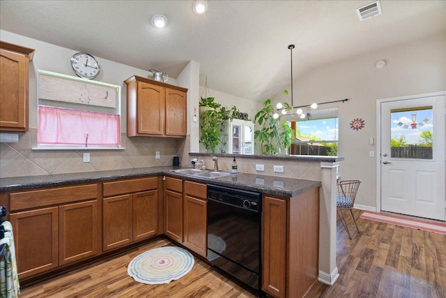 2321 Kale Dr, Austin, TX 78725 - kitchen with black dishwasher, a peninsula, light wood-style floors, backsplash, and vaulted ceiling