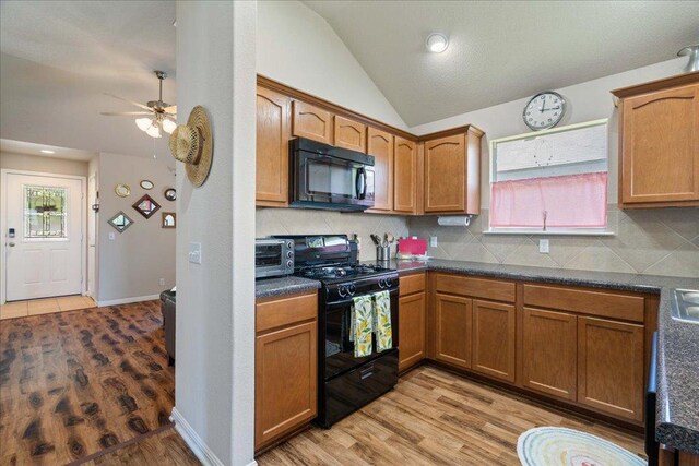 2321 Kale Dr, Austin, TX 78725 - kitchen featuring black appliances, vaulted ceiling, dark countertops, ceiling fan, and light wood-style floors