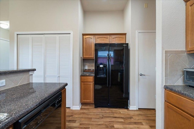 2321 Kale Dr, Austin, TX 78725 - kitchen featuring black appliances, light wood-style floors, backsplash, and dark stone counters