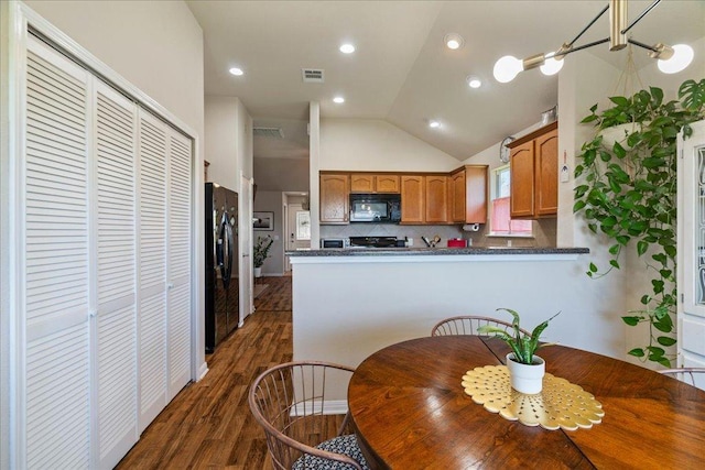 2321 Kale Dr, Austin, TX 78725 - kitchen with black appliances, lofted ceiling, dark wood finished floors, dark countertops, and decorative backsplash
