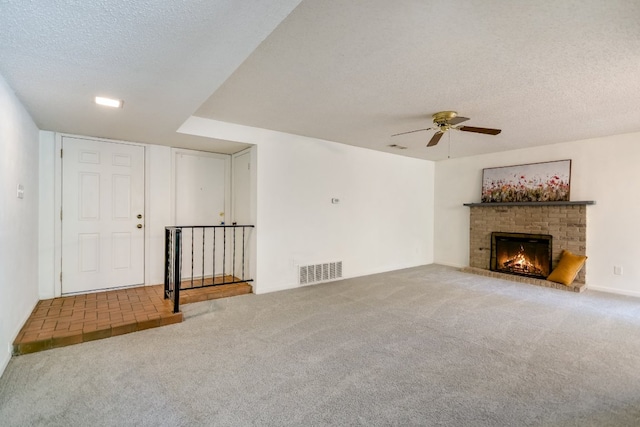 8702 Wildridge Dr, Austin, TX 78759 - unfurnished living room with carpet, a ceiling fan, a textured ceiling, and a fireplace