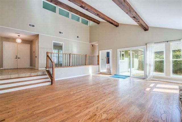 7507 Valburn Dr, Austin, TX 78731 - unfurnished living room featuring wood finished floors, beam ceiling, stairs, and high vaulted ceiling