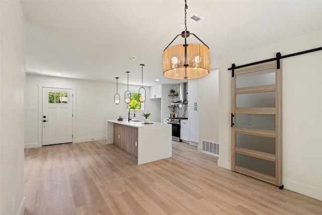5603 Darlington Ln, Austin, TX 78723 - kitchen with stainless steel range oven, a barn door, light wood-type flooring, white cabinets, and recessed lighting