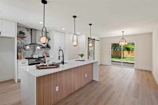 5603 Darlington Ln, Austin, TX 78723 - kitchen featuring wall chimney exhaust hood, stainless steel gas range, light wood-style floors, light countertops, and a barn door