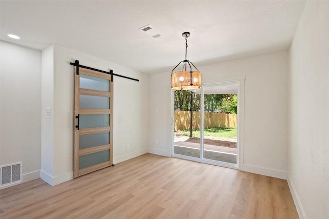5603 Darlington Ln, Austin, TX 78723 - empty room featuring a barn door, light wood-type flooring, and a chandelier