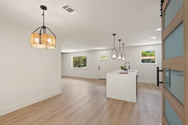 5603 Darlington Ln, Austin, TX 78723 - kitchen with recessed lighting, light wood-style flooring, healthy amount of natural light, a kitchen island with sink, and a chandelier