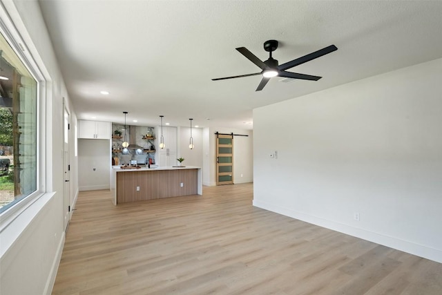 5603 Darlington Ln, Austin, TX 78723 - unfurnished living room featuring a barn door, light wood-style flooring, a ceiling fan, and recessed lighting